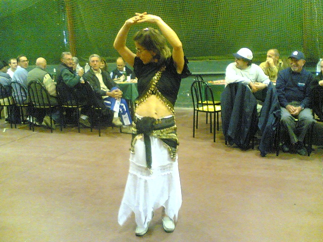 Foto di Loredana che danza in fusciacca, ha le braccia alzate e le mani incrociate sopra la testa mentre volteggia.